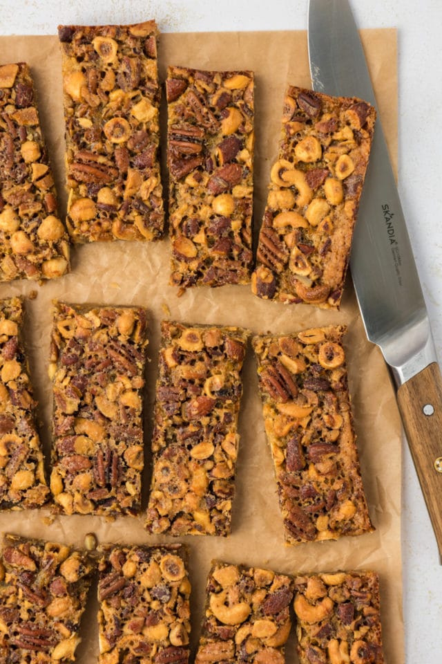 Overhead view of cut maple nut bars on parchment paper with knife