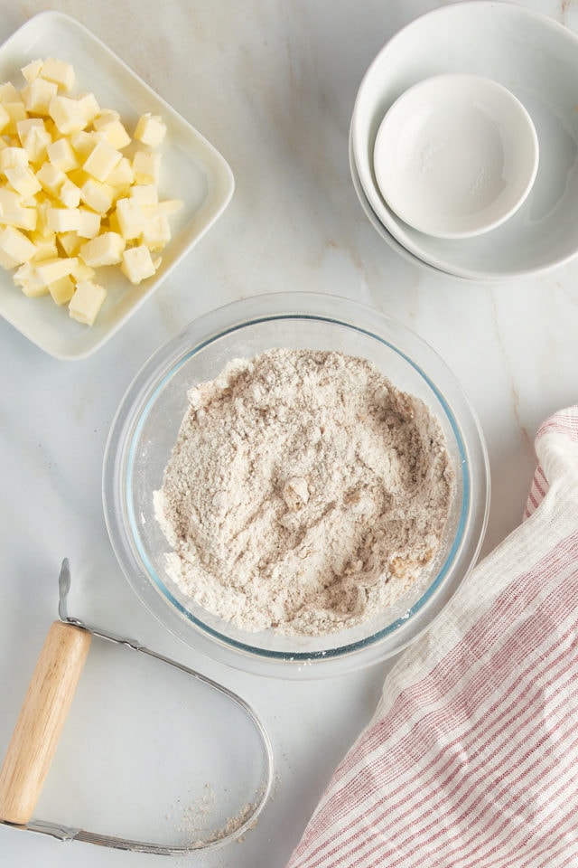 Overhead view of flour, brown sugar, cinnamon, and salt mixed in a glass bowl.