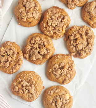 overhead view of crumb-topped apple cookies on a sheet of parchment paper