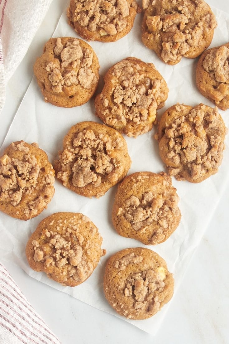 overhead view of crumb-topped apple cookies on a sheet of parchment paper