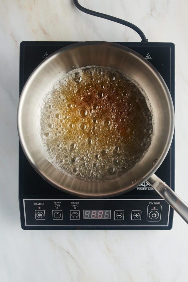 overhead view of amber-colored caramel cooking in a saucepan