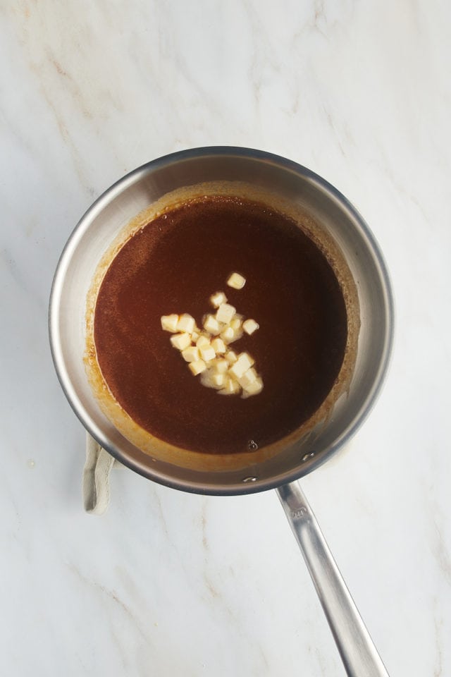 overhead view of pieces of butter added to caramel in a saucepan