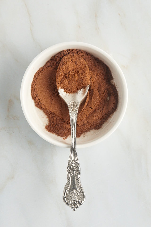 overhead view of a spoonful of Ceylon cinnamon in a shallow white bowl filled with more cinnamon
