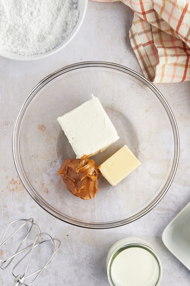 overhead view of cream cheese, butter, and cookie butter in a glass mixing bowl