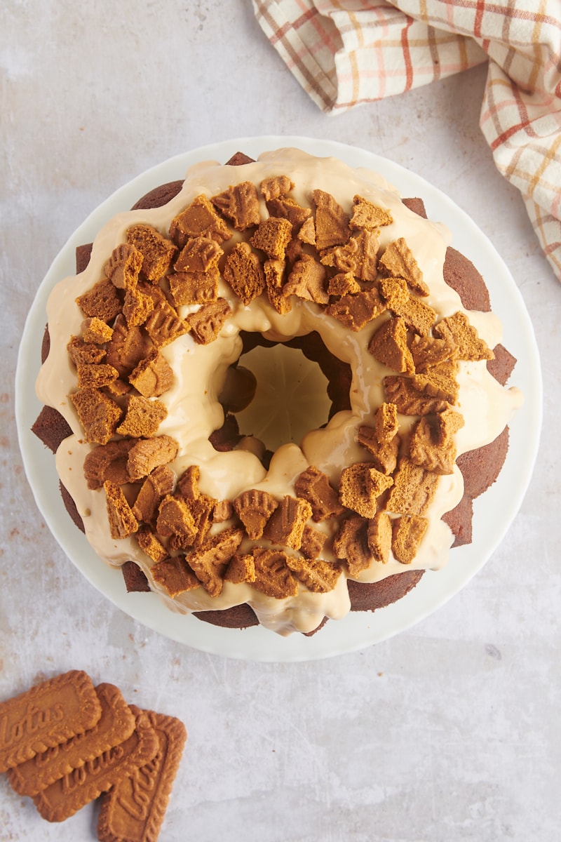 overhead view of glazed and garnished Cookie Butter Bundt Cake on a white cake stand