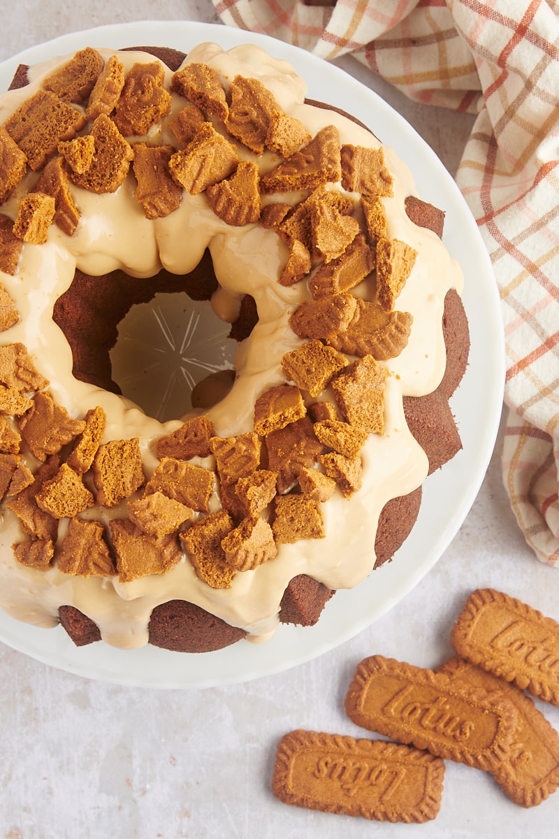 overhead view of Cookie Butter Bundt Cake on a white cake stand with speculoos cookies alongside