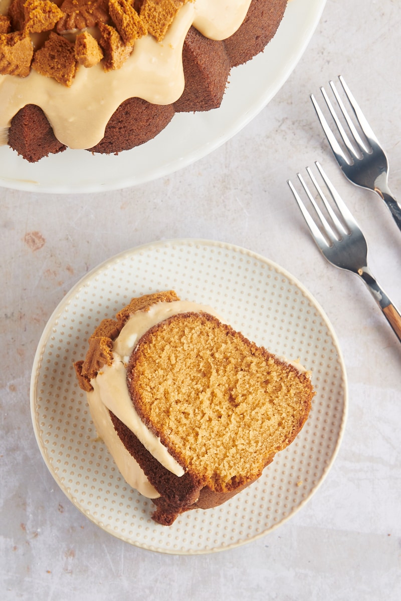 overhead view of a slice of Cookie Butter Bundt Cake on a white and beige plate with remaining cake alongside