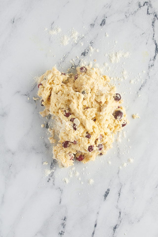 overhead view of cranberry orange scone dough on a floured marble surface