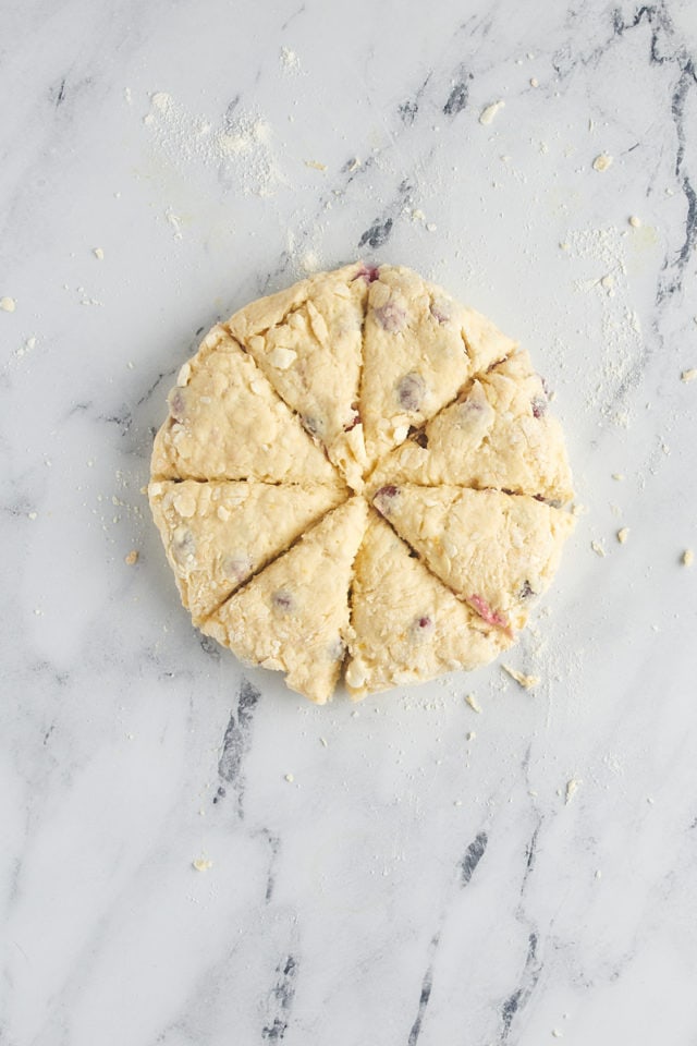 overhead view of cut cranberry orange scone dough on a marble surface