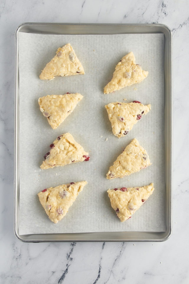 overhead view of cranberry orange scones on a parchment-lined baking pan ready to go into the oven