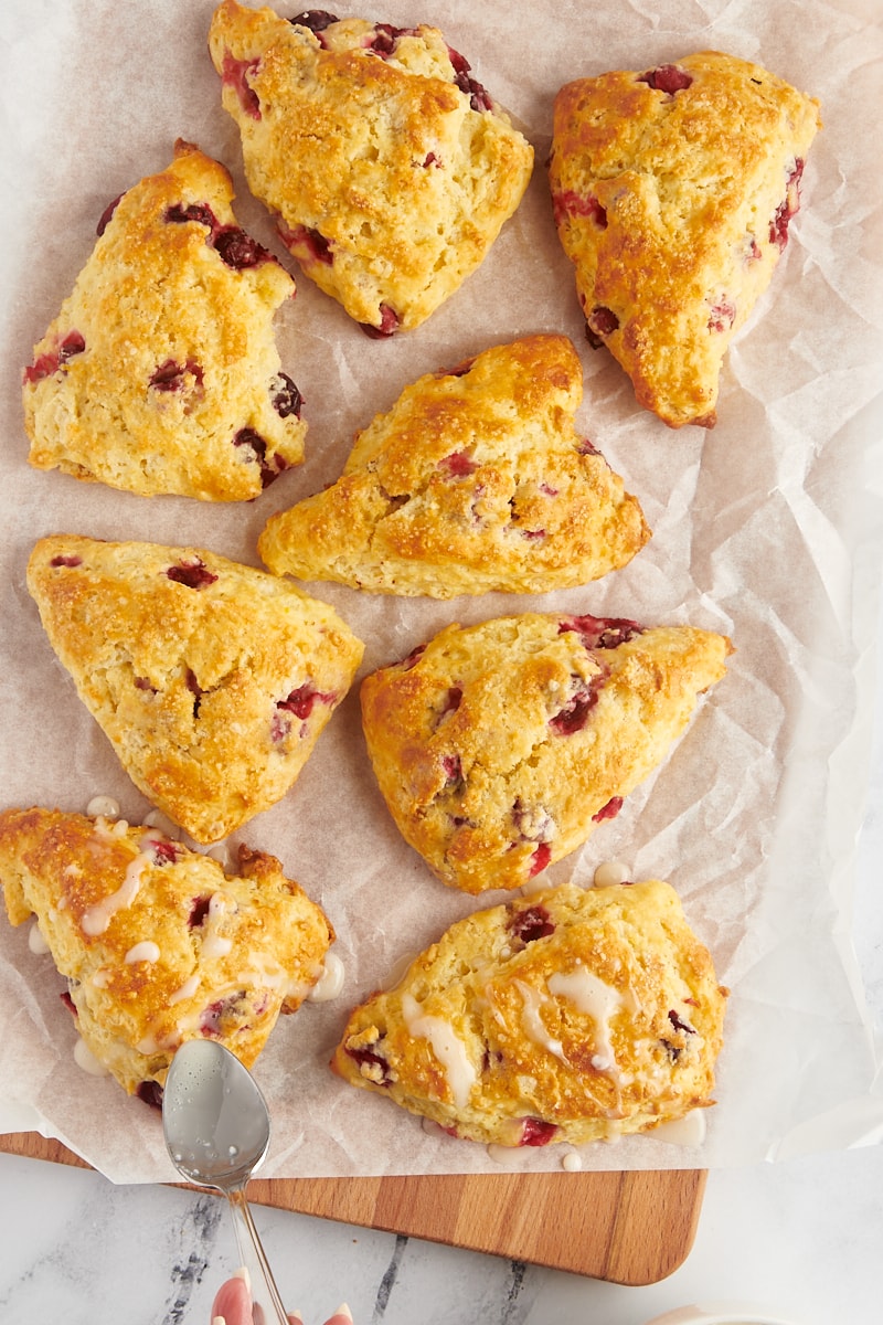 overhead view of a sweet orange glaze being drizzled over cranberry orange scones