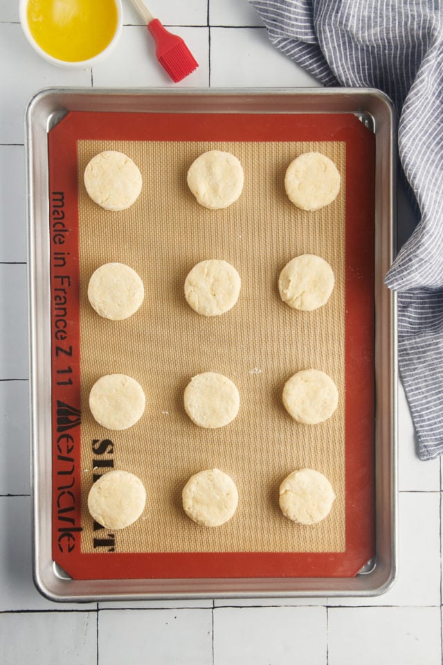 Overhead view of unbaked cream biscuits on silpat lined baking sheet