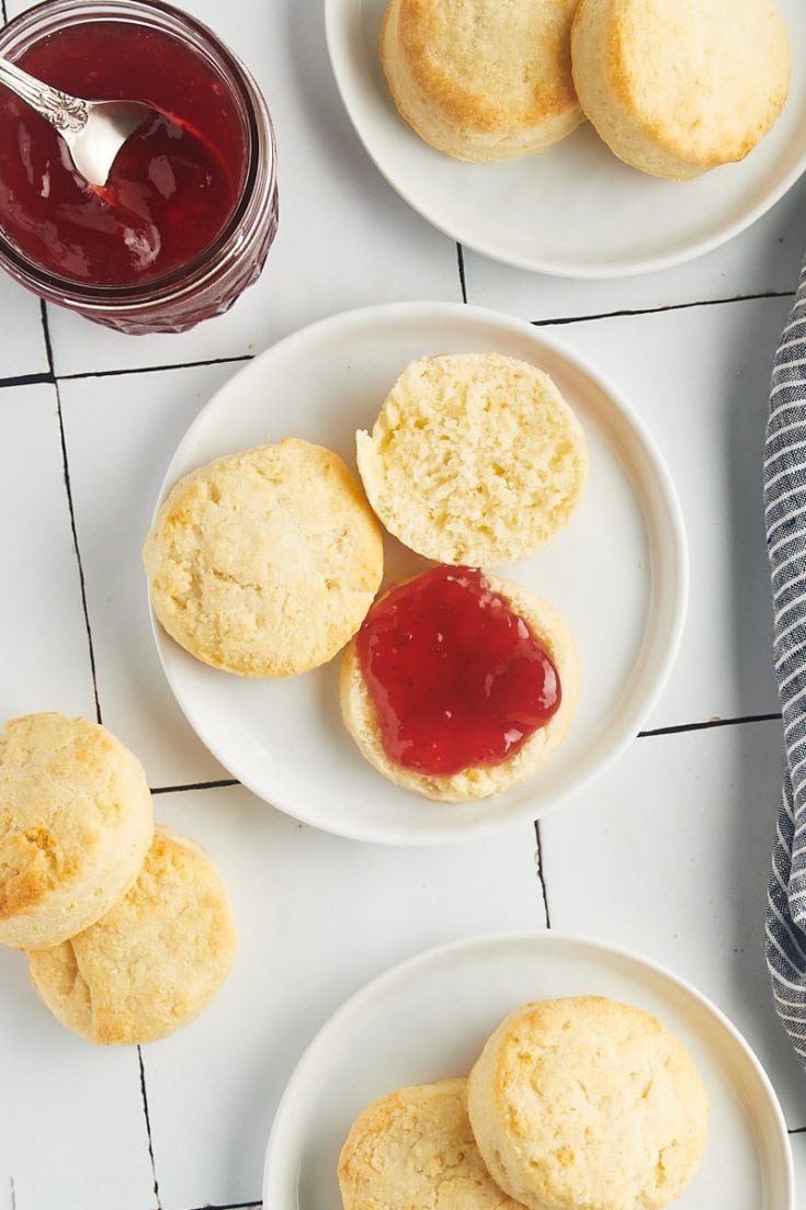 Overhead view of cream biscuits on plates with jam
