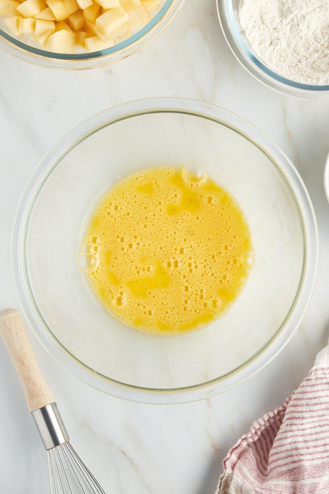 overhead view of lightly beaten eggs in a glass bowl