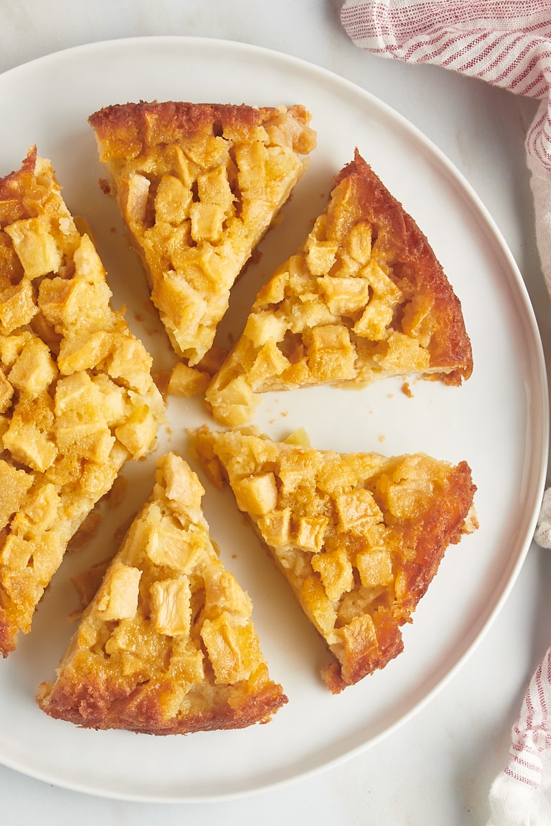 overhead view of partially sliced French apple cake on a white cake plate