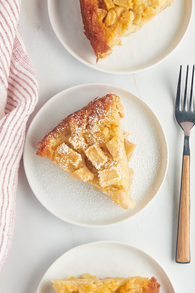 overhead view of a slice of French apple cake topped with confectioners' sugar