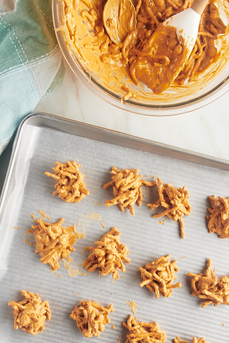 overhead view of butterscotch Haystacks on a baking sheet lined with wax paper with more of the mixture in a bowl