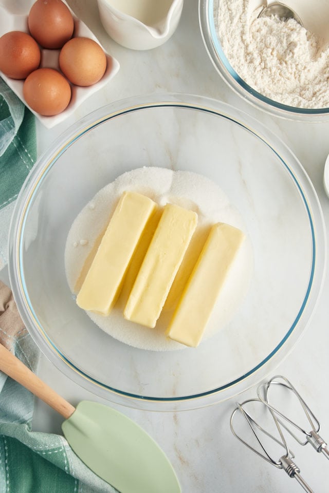 overhead view of butter and sugar in a glass mixing bowl