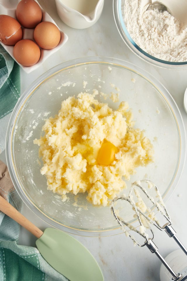 overhead view of an egg added to creamed butter and sugar