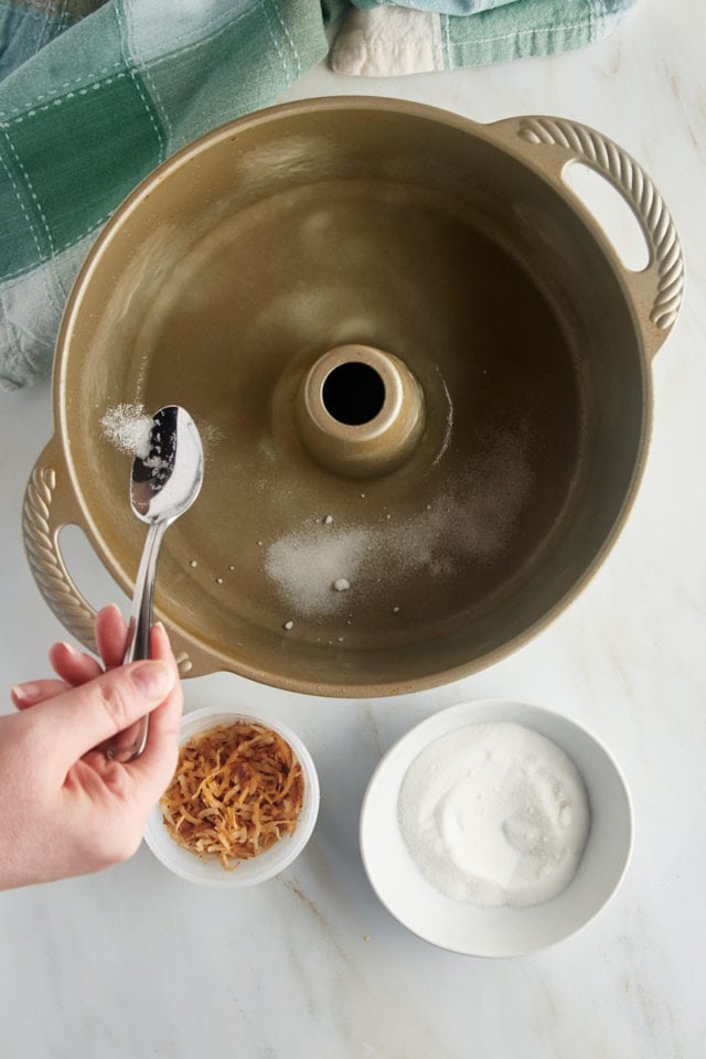 overhead view of sugar being sprinkled into the bottom of a tube pan