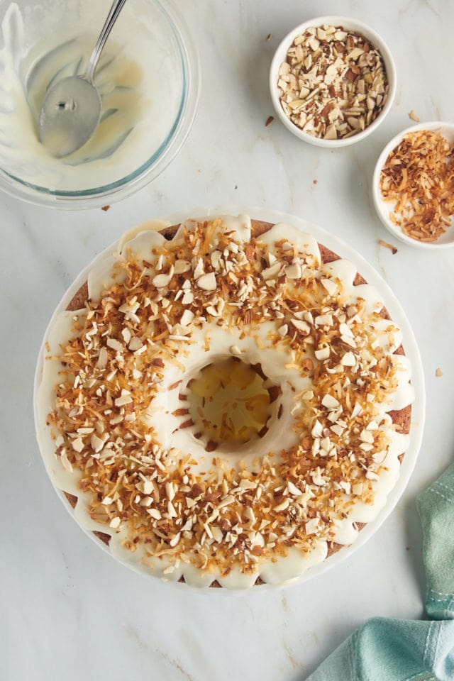 overhead view of Louisiana Crunch Cake topped with glaze, toasted coconut, and chopped almonds