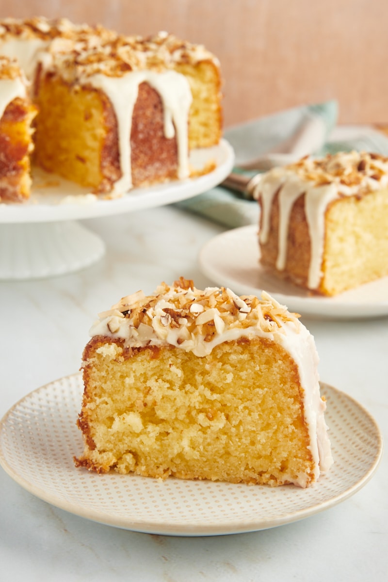 a slice of Louisiana Crunch Cake on a white and beige plate with more cake in the background