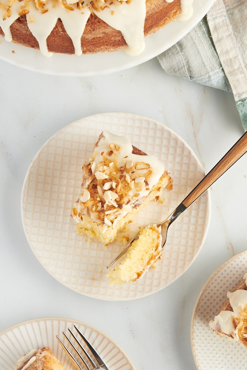 overhead view of a slice of Louisiana Crunch Cake on a white and beige plate with a bite of cake on a fork