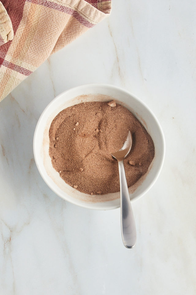 Overhead view of cinnamon sugar in a bowl with a spoon.