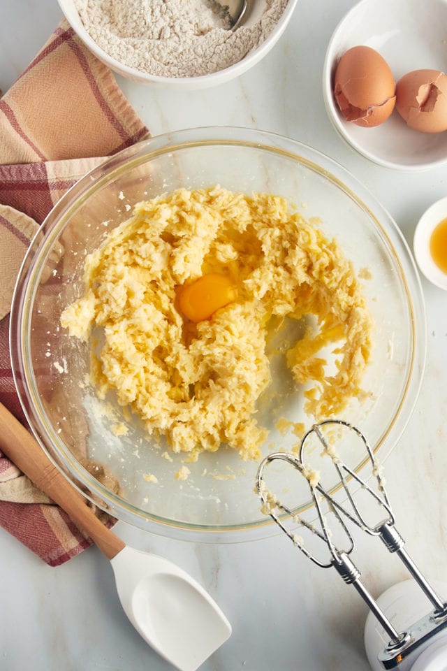 Overhead view of egg added to wet ingredients in a mixing bowl.