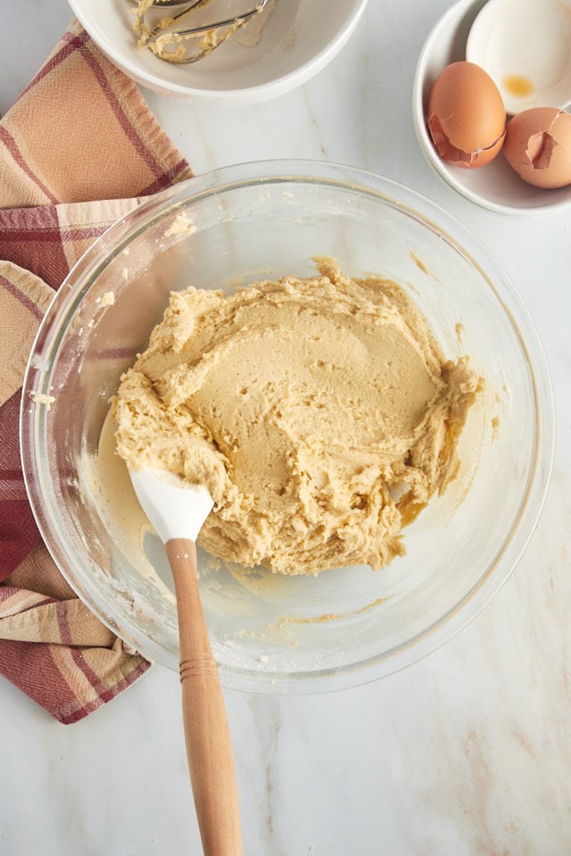 Overhead view of cookie dough in glass mixing bowl with rubber spatula