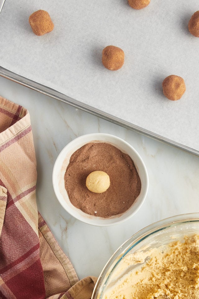 Overhead view of a dough ball in a bowl of cinnamon sugar.