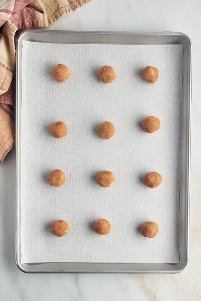 Overhead view of snickerdoodle dough balls on parchment lined baking sheet