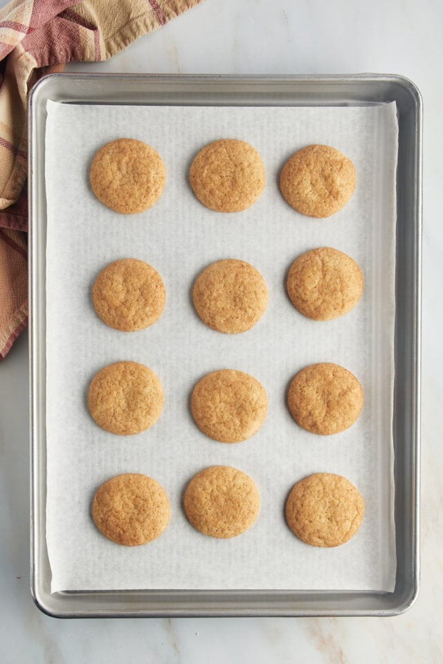 Overhead view of baked snickerdoodles on a parchment lined baking sheet.