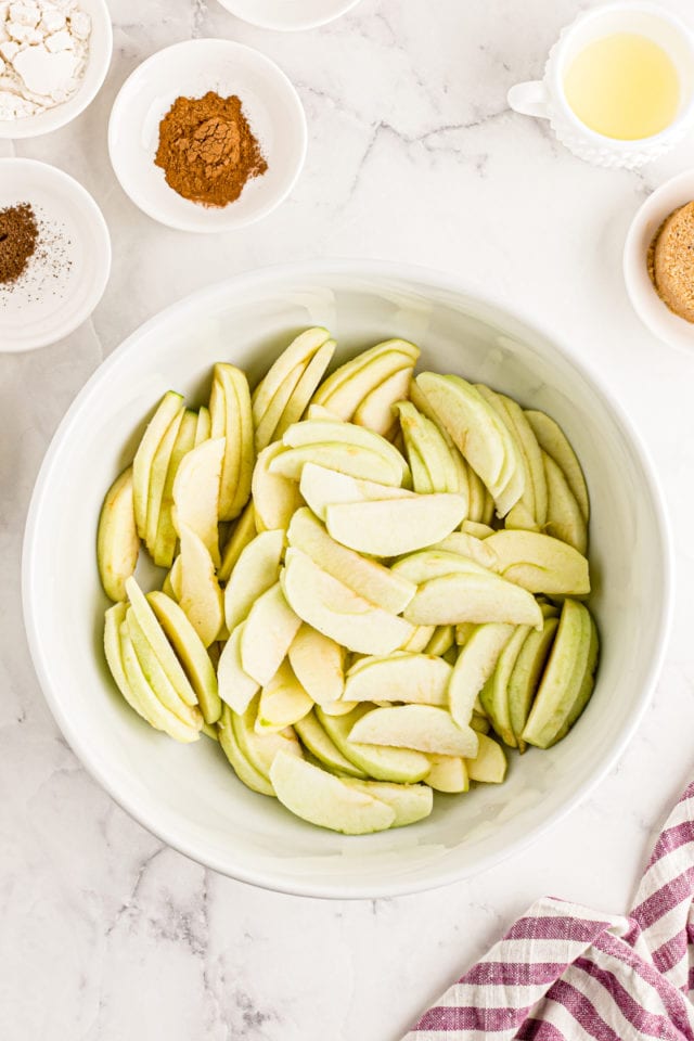 overhead view of sliced apples in a white mixing bowl