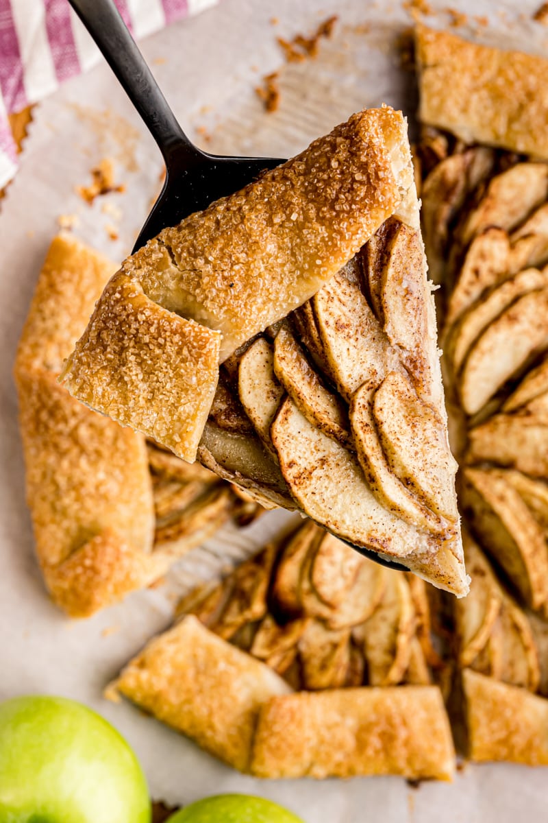 overhead view of a slice of apple galette on a pie server with the remaining pie in the background