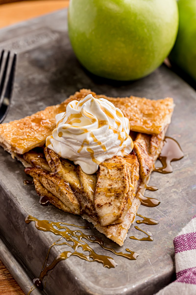 a slice of apple galette topped with whipped cream and caramel