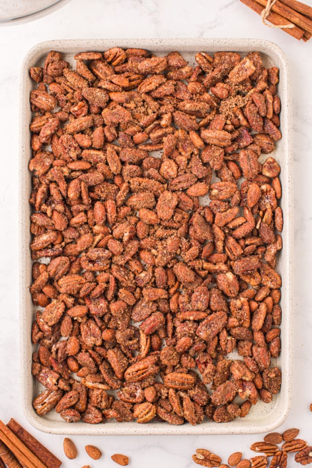 overhead view of candied nuts spread on a half sheet pan ready to go into the oven