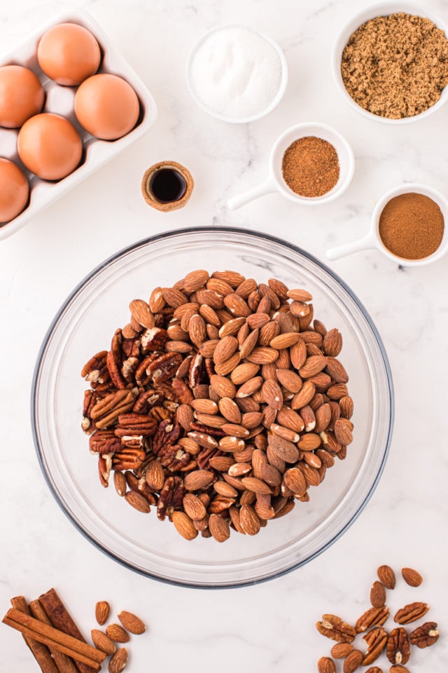 overhead view of pecan halves and whole almonds in a glass mixing bowl