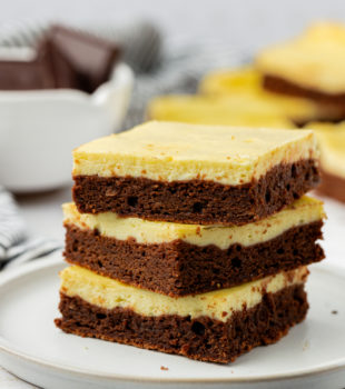 Stack of 3 cheesecake brownies on white plate