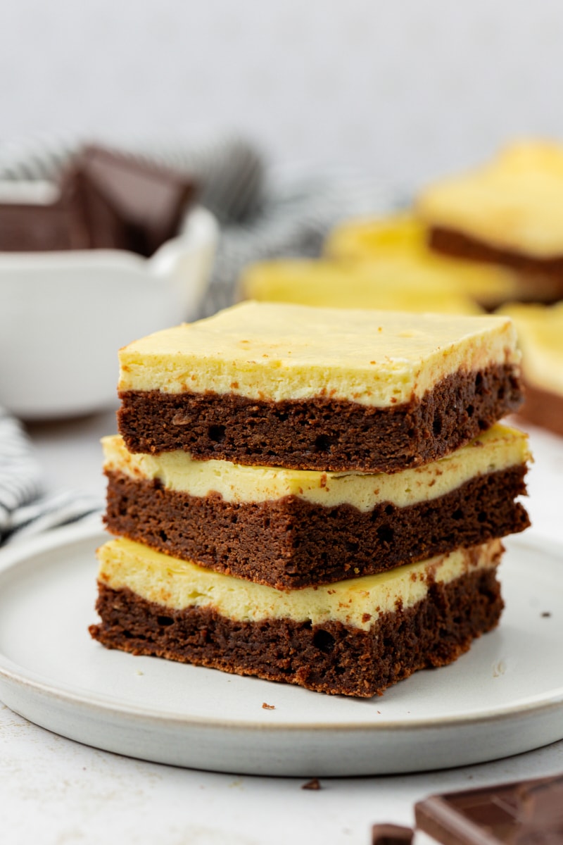Stack of 3 cheesecake brownies on white plate