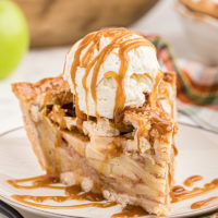 Old-fashioned apple pie on plate with scoop of vanilla ice cream and caramel drizzle