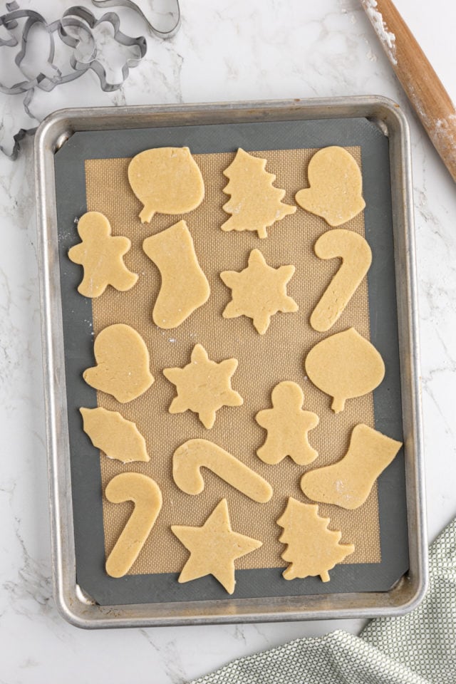 overhead view of cut-out sugar cookies on a silicone-lined baking sheet