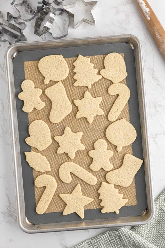 overhead view of freshly baked cut-out sugar cookies on a lined baking sheet