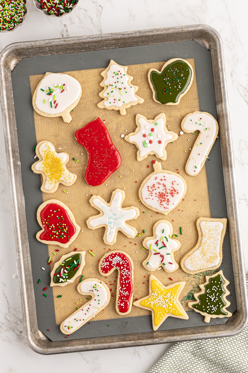 overhead view of decorated cut-out sugar cookies on a silicone-lined baking sheet