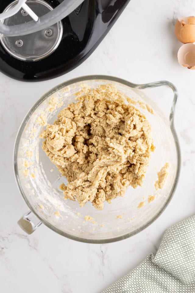 overhead view of mixed cut-out sugar cookie dough in the bowl of a stand mixer