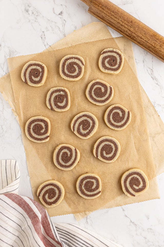 overhead view of sliced pinwheel cookie dough on parchment paper