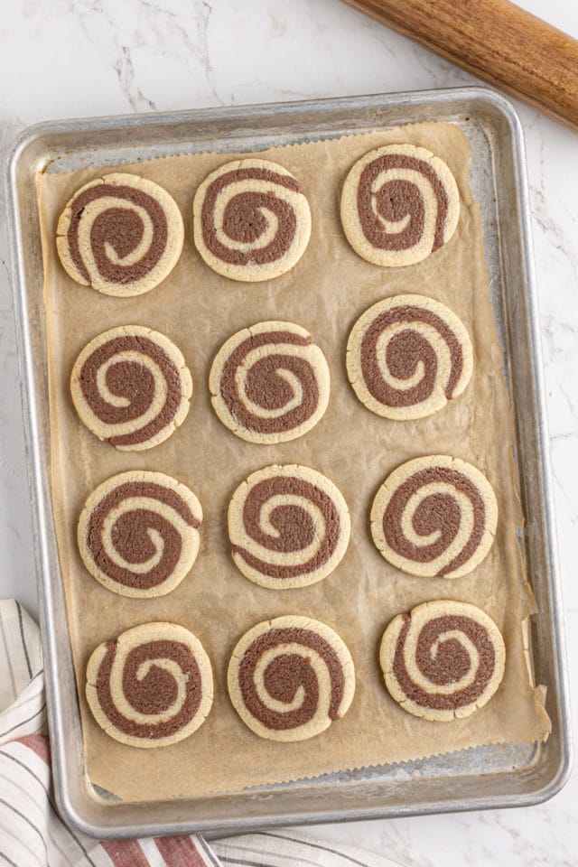 overhead view of freshly baked pinwheel cookies on a parchment-lined baking sheet