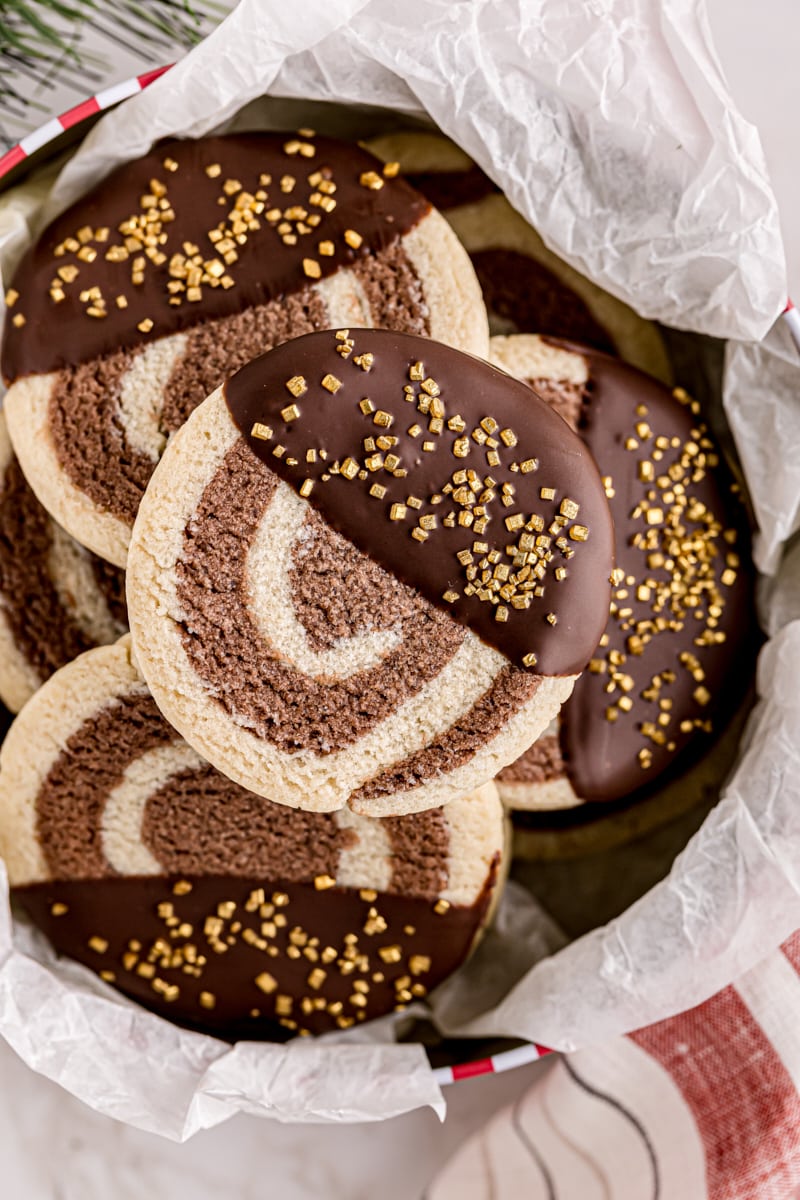 overhead view of chocolate-dipped pinwheel cookies in a cookie tin