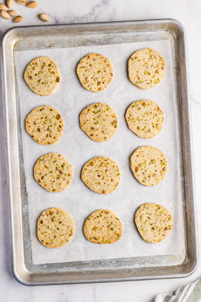 overhead view of freshly baked pistachio cookies on a parchment-lined baking sheet