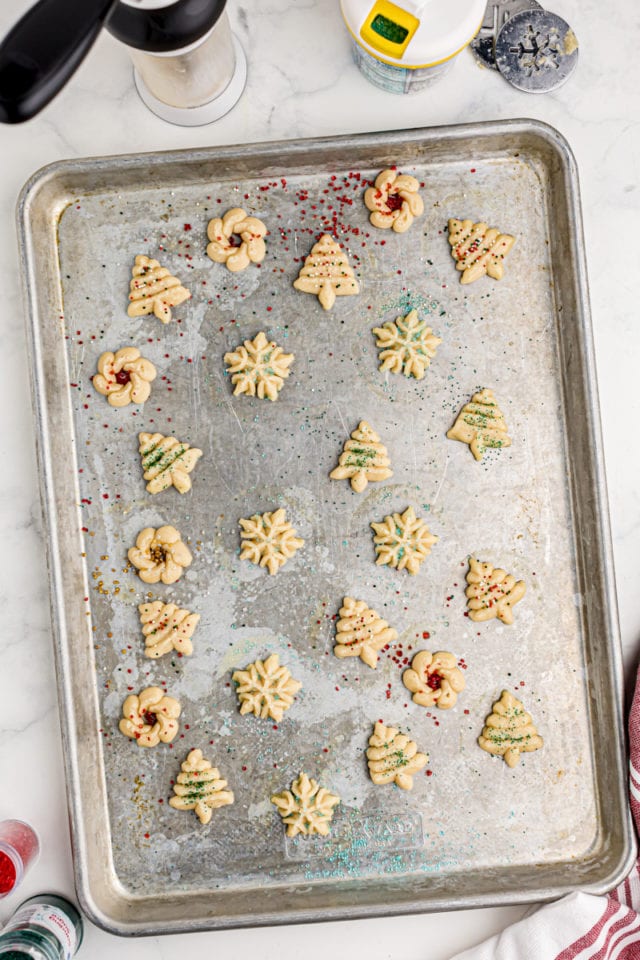overhead view of spritz cookies topped with sprinkles on a baking sheet